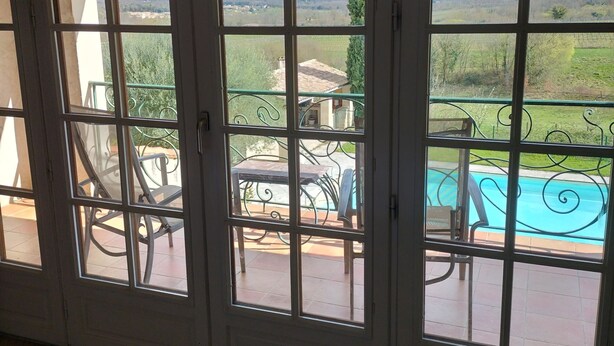 A room with a view of a swimming pool and patio furniture.