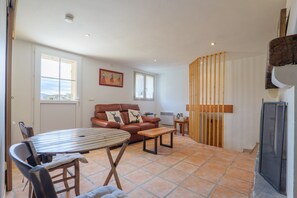 A living room with a sofa, a dining table, and a kitchen area with a stove.