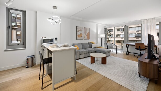 Een moderne woonkamer met een bank, salontafel en een eethoek met een magnetron.
