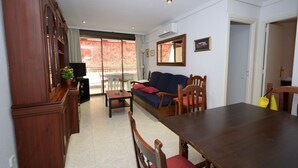 A living room with a sofa, wooden dining table, chairs, a TV, and a window with a view. - LAS Tejas 2-31 in Benidorm (Benidorm)