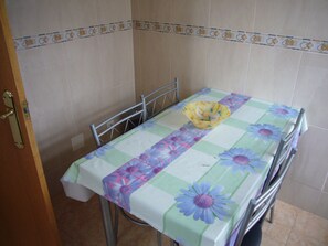 A small dining area with a table covered by a floral tablecloth, a metal chair, and a metal bench. - Eden Park 8C in Benidorm (Benidorm)