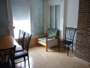 A dining area with a wooden table, four chairs, a cushioned bench, and a brick wall. - Eden Park 8C in Benidorm (Benidorm)