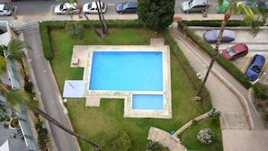 Une piscine rectangulaire avec un petit jacuzzi attenant, le tout entouré d’une pelouse bien entretenue et de palmiers.