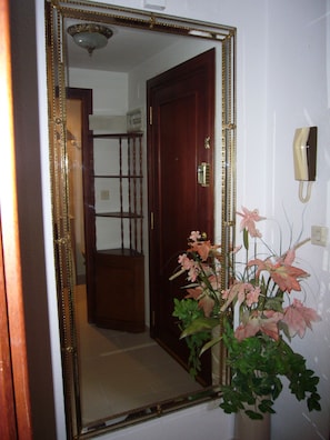 A hallway with a large mirror, a wooden door, a telephone, and a potted plant. - Gemelos 12 10c1 in Benidorm (Benidorm)
