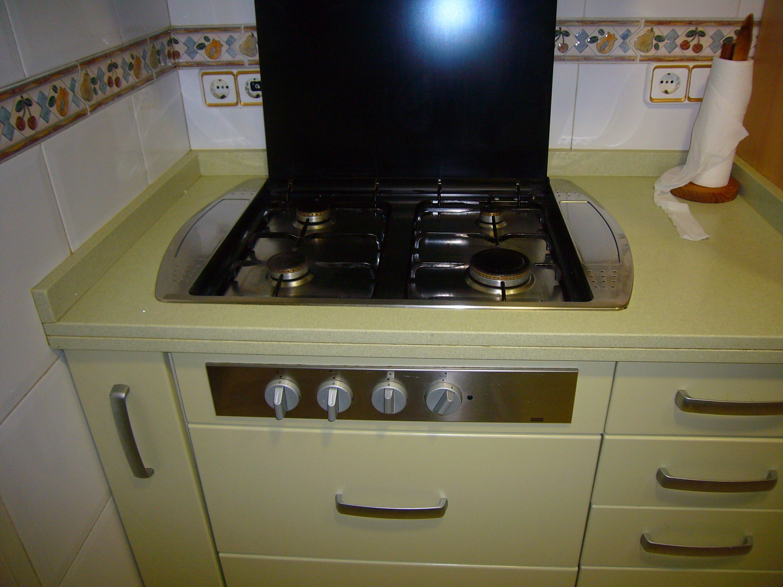 Una cocina con estufa, cuatro hornillas y un panel de control con cuatro perillas.