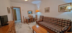 A living room with a sofa, a TV, a dining table with chairs, and a lamp. - Paraiso Esperanto 4B (Benidorm)