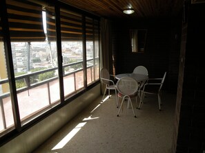 A balcony with a view of a cityscape, a table with chairs, and a hanging light fixture. - LOS Pinos 12B in Benidorm (Benidorm)