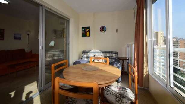 A room with a dining table, chairs, a sofa, and a window with a view of buildings. - LA Pinta 11B in Benidorm (Benidorm)