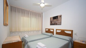 A hotel room with two beds, a ceiling fan, a painting, and a bedside table. - LA Pinta 11B in Benidorm (Benidorm)