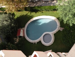 Vista aèria d'una piscina de forma singular, envoltada per gespes cuidades i arbres.