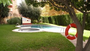 A swimming pool with a lifebuoy, surrounded by a well-maintained lawn and a building in the background. - Gijon 9B in Benidorm (Benidorm)