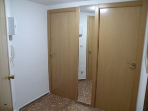 A room with two wooden doors, a white wall, and a tiled floor. - Gijon 9B in Benidorm (Benidorm)