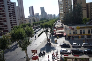 A city street with tall buildings, trees lining the road, and parked cars. - Coblanca 3 36 in Benidorm (Benidorm)