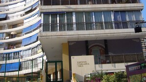 Et hotel med flere etager, en buet facade, altaner og et skilt, der angiver, at det er Edificio Cobblanca Tres.