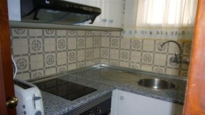 Una cucina compatta con tostapane integrato, lavello e piano cottura.