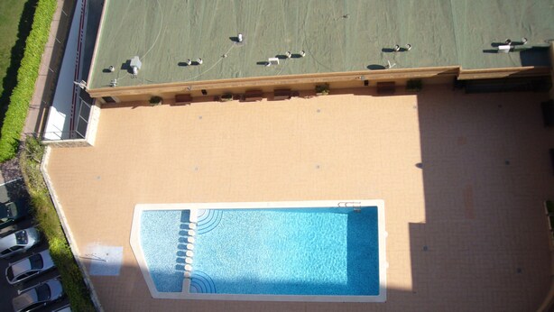 An aerial view of a swimming pool surrounded by a parking area and a building with a flat roof. - Finlandia 10D in Benidorm (Benidorm)