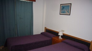 A room with two beds, a nightstand with a lamp, a painting on the wall, and a blue curtain. - Finlandia 10D in Benidorm (Benidorm)