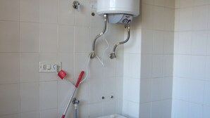 A laundry room with a front-loading washing machine, a red mop, and a white water heater on the wall. - Finlandia 10D in Benidorm (Benidorm)