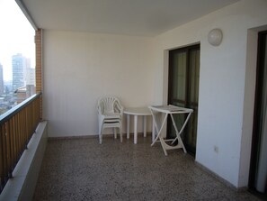 A balcony with a white chair, a small table, and a window. - Finlandia 10D in Benidorm (Benidorm)