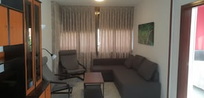 A living room with a sofa, armchair, and a small table. There is a window with curtains, a lamp, and a painting on the wall. - Gemelos 12 2D1 in Benidorm (Benidorm)