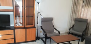A living room with a TV, wooden cabinet, two grey armchairs, and a coffee table. - Gemelos 12 2D1 in Benidorm (Benidorm)