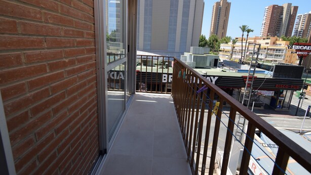 A balcony with a view of a commercial area, including a store with a 'DISCO-PUR' sign. - Oce3 3A in Benidorm With 2 Bedrooms and 1 Bathrooms (Benidorm)