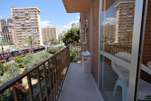 A balcony with a view of high-rise buildings, a small table, and a trash bin. - Oce3 3A in Benidorm With 2 Bedrooms and 1 Bathrooms (Benidorm)