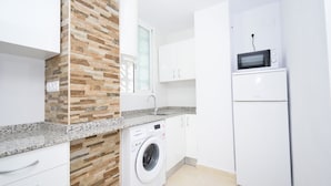 A compact kitchen with a washing machine, a microwave, and white cabinets. - Oce3 3A in Benidorm With 2 Bedrooms and 1 Bathrooms (Benidorm)