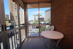 A balcony with a white table and chairs, a view of a cityscape with tall buildings, and a clear sky. - Oce3 3A in Benidorm With 2 Bedrooms and 1 Bathrooms (Benidorm)