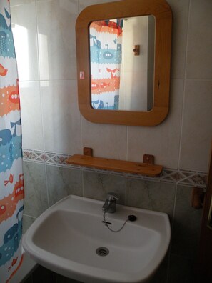 A bathroom with a white sink, a wooden-framed mirror, and a shower curtain with a fish pattern. - Kennedy 1 12A in Benidorm (Benidorm)