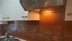 Una cocina con armarios blancos, encimera negra, pileta de acero inoxidable y horno empotrado.