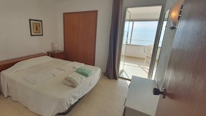 Un dormitorio con cama, mesitas de noche, armario y balcón con vistas.