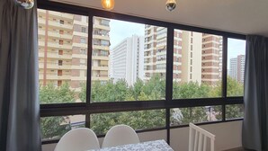 A room with a large window, a table with two chairs, and a radiator. - Mariscal 3 4J 2 Dormitorios (Benidorm)