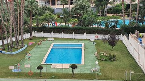A swimming pool surrounded by palm trees and a white fence. - Mariscal 3 4J 2 Dormitorios (Benidorm)