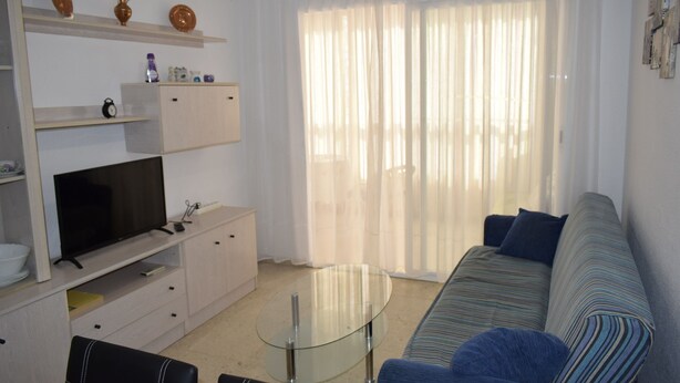 A modern living room with a sofa, television, and glass coffee table. - Karola 8D in Benidorm (Benidorm)
