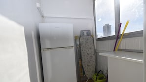 A compact kitchen with a refrigerator, a drying rack, and a window with a view of buildings. - Karola 9A in Benidorm (Benidorm)