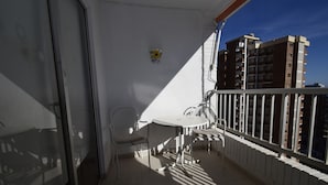 A balcony with a table and chairs, a white railing, and a view of buildings. - Karola 9A in Benidorm (Benidorm)