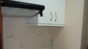 Una cocina compacta con armarios blancos, un lavamanos de acero inoxidable y una estufa negra.