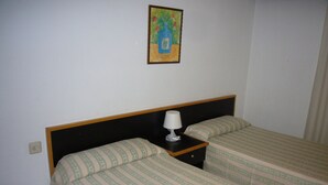 Un dormitorio con dos camas, una mesita de noche, una lámpara y un cuadro en la pared.