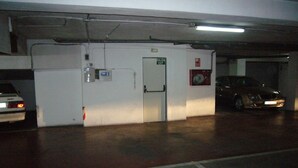 Un garaje para estacionamiento con una puerta de salida blanca, un extintor y un coche dentro.