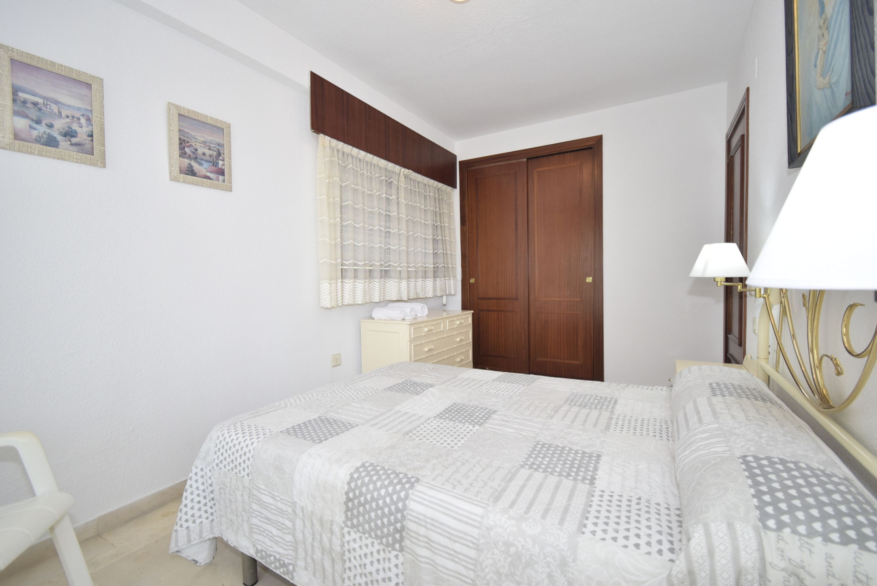 A bedroom with a bed, a dresser, a chair, and a door.