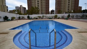 A swimming pool with a tiled edge and metal ladders, surrounded by a low wall and benches. - Gemelos 4 3C1 in Benidorm (Benidorm)