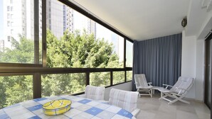 A balcony with a checkered table, two chairs, and a view of trees and buildings. - Gemelos 4 3C1 in Benidorm (Benidorm)