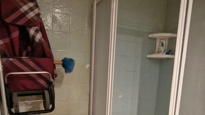 Ein kleines Badezimmer mit Waschmaschine, Duschkabine und Toilette.