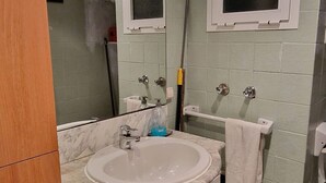 Ein Badezimmer mit Waschbecken, Spiegel, Handtuchhalter und einem Holzschrank.