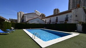 A rectangular swimming pool with a ladder, surrounded by artificial grass, and adjacent to a building with balconies. - Rinconada Real 159 in Benidorm (Benidorm)