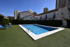 A rectangular swimming pool with a ladder, surrounded by artificial grass, and adjacent to a building with balconies. - Rinconada Real 159 in Benidorm (Benidorm)