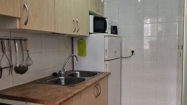 A compact kitchen with light wooden cabinets, a white stove, a microwave, and a sink. - Rinconada Real 159 in Benidorm (Benidorm)