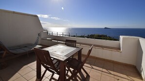 A balcony with a table and chairs, overlooking a coastal view with the sea and a small island. - Villamarina A517 in Benidorm (Benidorm)