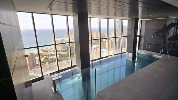 Una piscina interior moderna con grandes ventanales que ofrecen vistas a la ciudad.